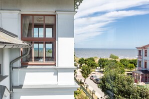 Un balcone con vista sul mare e una strada con auto parcheggiate.
