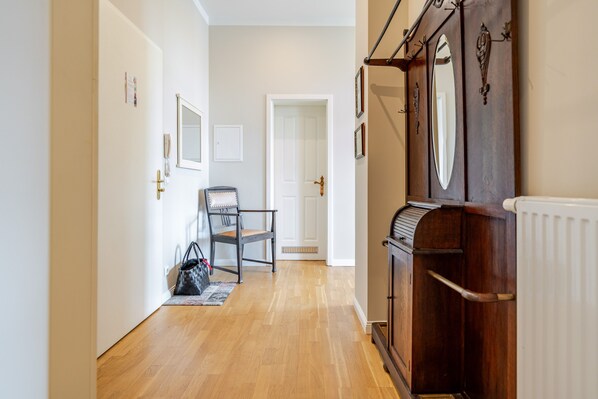 A hallway with a wooden floor, a chair, a radiator, and a door at the end.