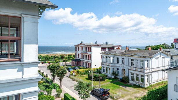 Un quartier résidentiel situé sur la côte, avec de grands immeubles blancs, une route et une vue sur la mer.