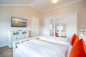 Une chambre avec deux lits, une commode, une armoire et un tableau au mur.