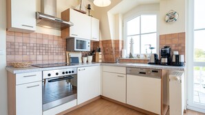 Een moderne keuken met witte kastjes, een roestvrijstalen oven, een magnetron en een koffiezetapparaat.