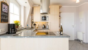 Eine moderne Küche mit einer Edelstahl-Dunstesse, einer eingebauten Mikrowelle und einer Arbeitsplatte aus Granit.
