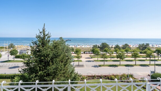 A coastal view with a clear sky, a beach with umbrellas, and a parking area with trees. - Villa Dora, App. 07, Germany (Heringsdorf)