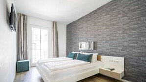 Une chambre d’hôtel moderne dotée d’un grand lit, d’un téléviseur fixé au mur et d’un mur décoratif à l’aspect pierre.