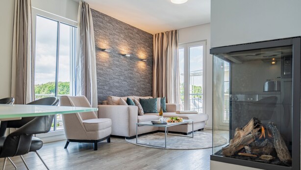 Un salon moderne avec un mur d’accent en pierre, une table basse en verre et une cheminée.