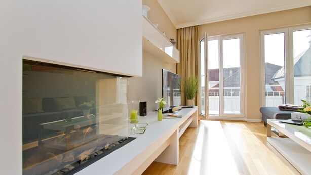 A modern living room with a large flat-screen TV, a glass fish tank, a coffee table, and a sofa.