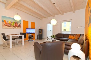 Una sala de estar moderna con comedor, televisor y sofá.