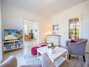 Ein Wohnzimmer mit Fernseher, Bücherregalen, Kamin und Essbereich.