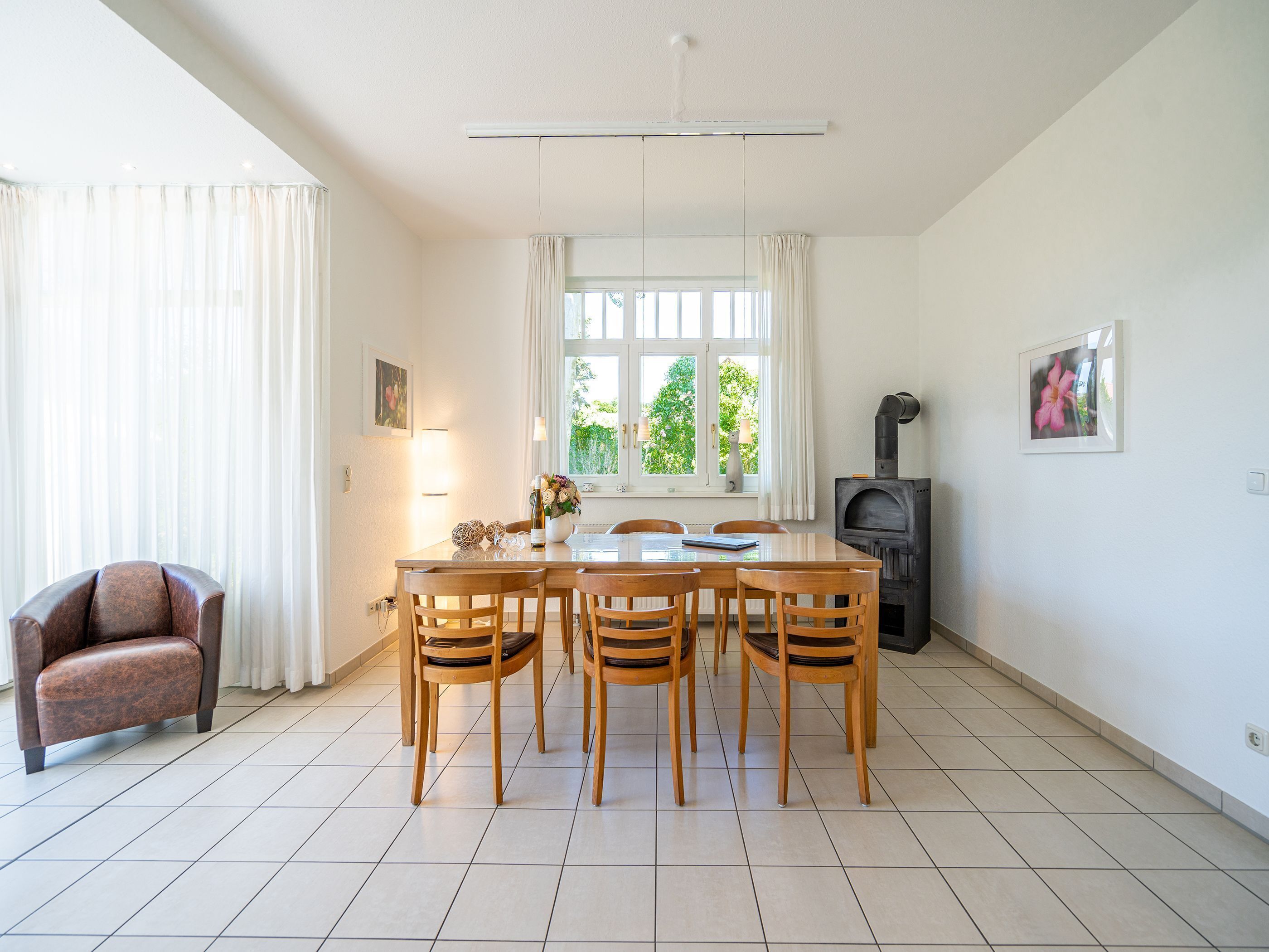 A dining area with a table and chairs, a sofa, a fireplace, and a window with curtains.