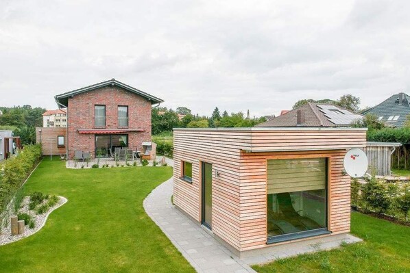 Ein modernes Haus mit Ziegelaußenwand und Anbau aus Holz.