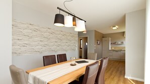 En matplats med ett träbord, bruna stolar, en vit duk och en modern hänglampa.