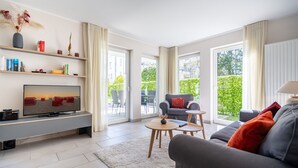 A modern living room with a flat-screen TV, a grey sofa, a coffee table, and a bookshelf. - Seeresidenz Haus Atlantic, App. C02 (Heringsdorf)