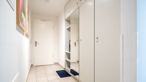 A hallway with a white door, a mirrored wardrobe, and a blue rug. - Seeresidenz Haus Atlantic, App. C02 (Heringsdorf)
