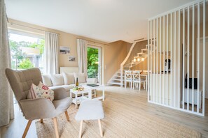A modern living room with a sofa, coffee table, and ottoman. There is a staircase leading to an upper level.