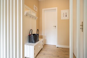 A hallway with a white bench, a coat rack, and a door.