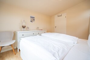A bedroom with a bed, a dresser, a chair, and a door.
