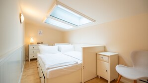 Ein Schlafzimmer mit Oberlicht, einem Bett, einem Nachttisch, einem Stuhl und einem Beistelltisch.