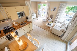 Eine moderne Küche mit Essbereich, einer Couch und Blick ins Freie.