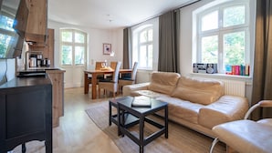 Un salon moderne comprenant un canapé, une table basse et un coin repas avec des chaises et une table.