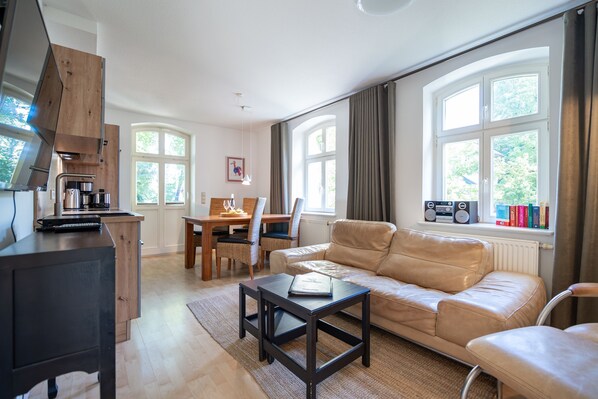 A modern living room with a sofa, coffee table, and a dining area with chairs and a table.