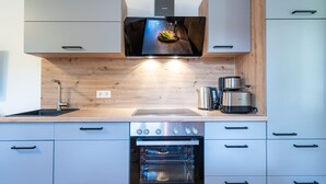 Une cuisine moderne dotée d’un four encastré, d’une machine à café et d’un pare-feu en bois.