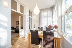 Un espace repas moderne avec une table en verre, des chaises en cuir et un luminaire suspendu.