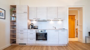 A modern kitchen with white cabinetry, a built-in oven, and a coffee machine. - Villa Medici Heringsdorf, App. 07 (Heringsdorf)