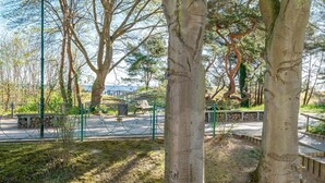 A park with trees, benches, and a paved walkway. - Villa Medici Heringsdorf, App. 07 (Heringsdorf)