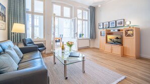 A modern living room with a glass coffee table, leather sofa, and wooden cabinets. - Villa Medici Heringsdorf, App. 07 (Heringsdorf)