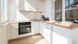 Eine moderne Küche mit weißen Schränken, einer Holzarbeitsplatte und einem Backofen.