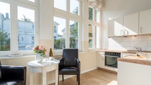 Eine moderne Küche mit großen Fenstern, einem Essbereich mit Tisch und Stühlen sowie Blick auf die Stadt.