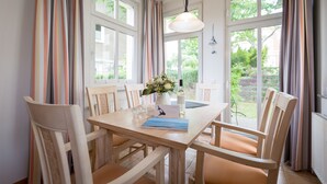 En matplats med ett träbord, stolar, en vas med blommor och en hängande lampa.
