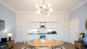A modern kitchen with white cabinetry, a round wooden dining table, and a central island.