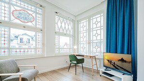 A modern living room with a TV, a green chair, and a desk.