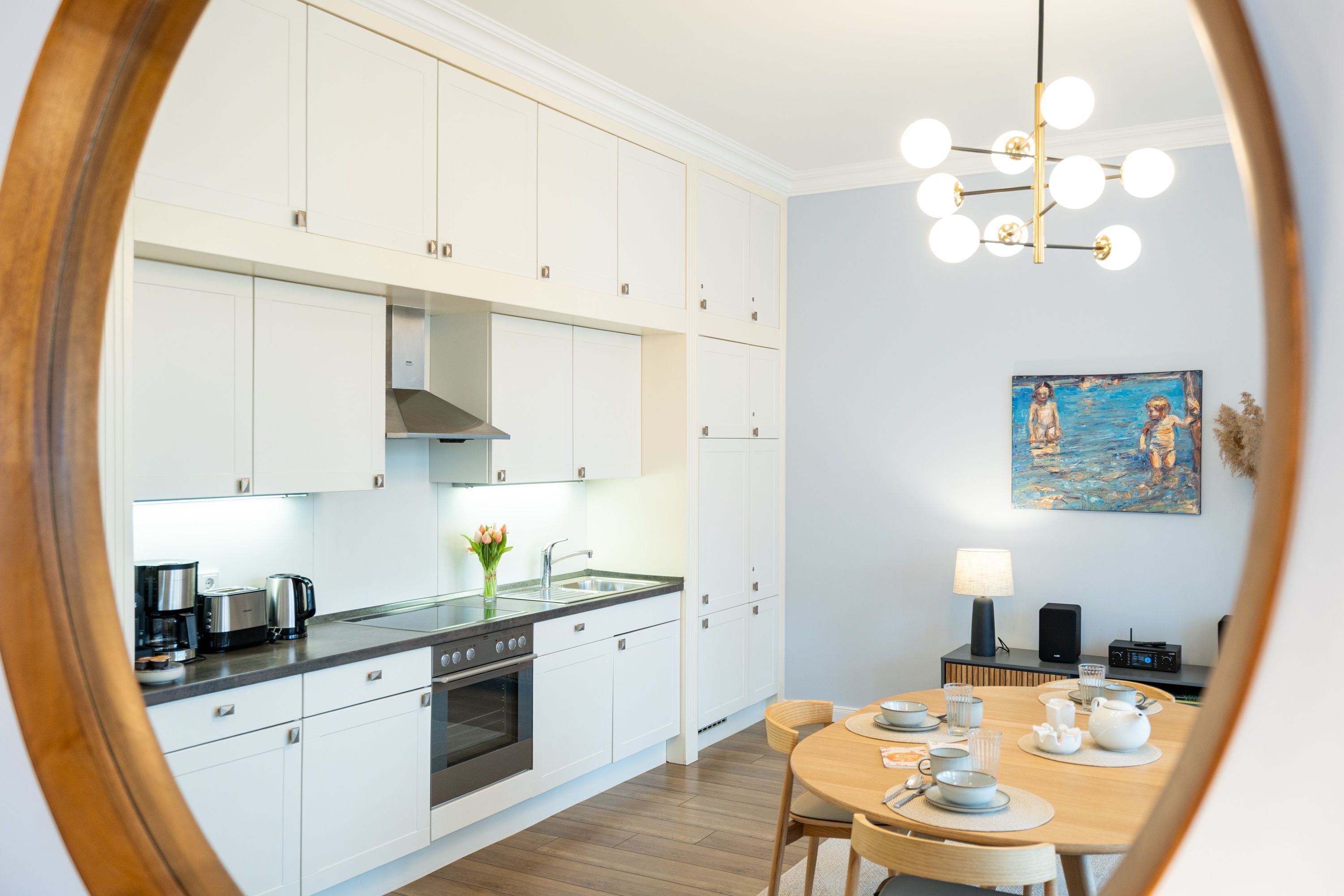 Una cocina moderna con armarios blancos, una estufa y un comedor con una mesa preparada para dos personas.