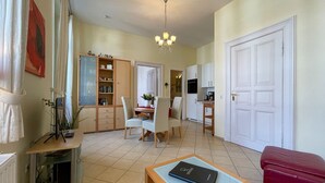 A spacious living area with a dining table, chairs, a red sofa, a wooden coffee table, and a bookshelf. - Villa Goodewind, App. 4 (Heringsdorf)
