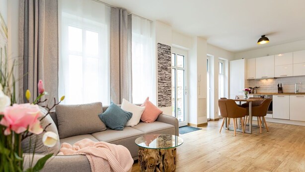 Ein modernes Wohnzimmer mit einer Couch, einem Glastisch und einem Essbereich mit Stühlen.