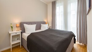 Ein Schlafzimmer mit Bett, Nachttisch, Lampe und Vorhängen.
