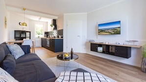A modern living room with a sofa, a coffee table, and a TV mounted on the wall. - Haus am Schmollensee, app. 7i (Heringsdorf)