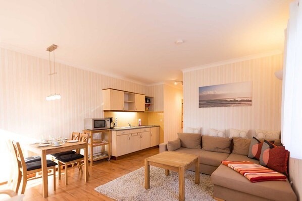 A compact living space with a dining area, kitchenette, and a sofa with a view.