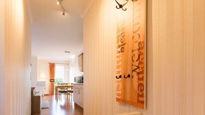 A hallway with a wooden wall and a white radiator. There is a dining area with a table and chairs in the background. - Maxine, Trassenheide (Baltic seaside resort), Germany (Trassenheide)