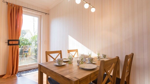 A dining area with a wooden table set for four, surrounded by chairs. - Maxine, Trassenheide (Baltic seaside resort), Germany (Trassenheide)