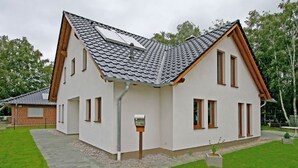 A modern two-story house with a sloped roof, a small attached garage, and a well-maintained lawn. - Maxine, Trassenheide (Baltic seaside resort), Germany (Trassenheide)