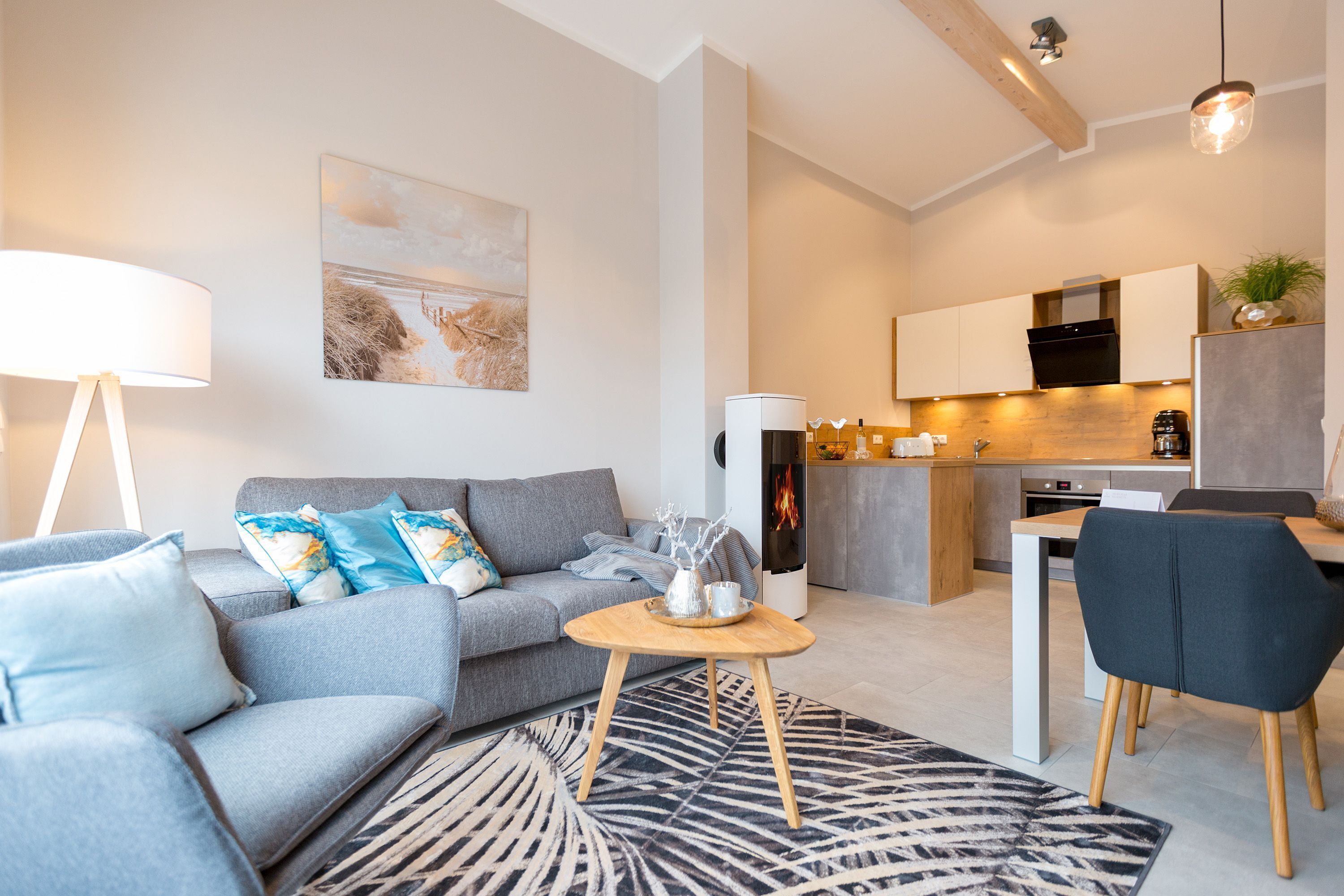 A modern living room with a grey sofa, a coffee table, and a dining area with a chair.