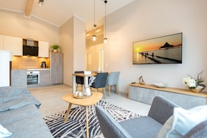 A modern living room with a sofa, a coffee table, and a dining area with chairs and a table.