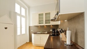 A modern kitchen with wooden flooring, white cabinetry, and a dark countertop. - Schloss am Meer, App. 4 (Heringsdorf)