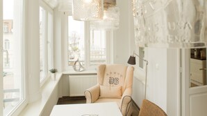 A modern interior with a large window, a table, and a chair with a number on it. - Schloss am Meer, App. 4 (Heringsdorf)