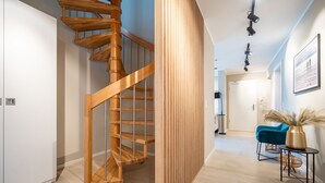 Un interno moderno con una scala a chiocciola in legno, una poltrona blu e un vaso con pannocchie di pampa.