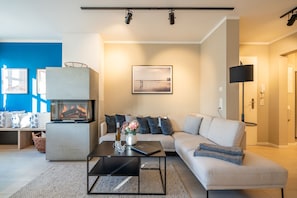 A modern living room with a sofa, a coffee table, a TV, and a fireplace.