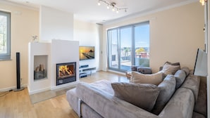 Un salon moderne avec une cheminée, un canapé, un téléviseur et un balcon offrant une vue agréable.